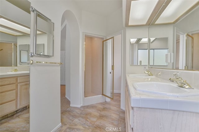 full bathroom featuring a stall shower, a sink, and double vanity