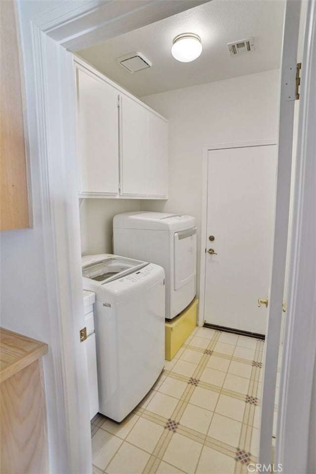 clothes washing area featuring light floors, visible vents, washer and clothes dryer, and cabinet space