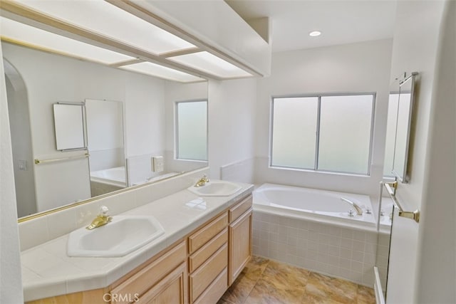 full bathroom with a bath, double vanity, and a sink