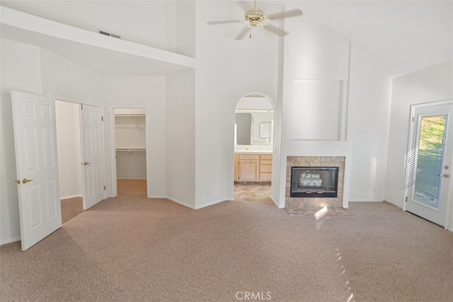 unfurnished living room with visible vents, baseboards, light colored carpet, a high ceiling, and a fireplace