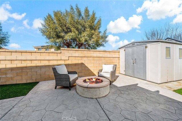 view of patio / terrace with an outbuilding, a fenced backyard, an outdoor fire pit, and a shed