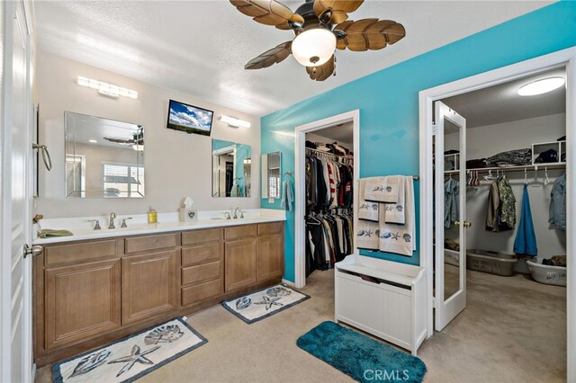 bathroom with a ceiling fan, a walk in closet, a sink, and double vanity