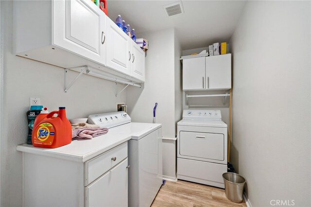 laundry room with separate washer and dryer, cabinet space, light wood-style flooring, and visible vents