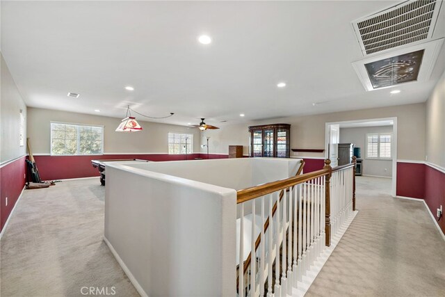 corridor with plenty of natural light, an upstairs landing, visible vents, and light colored carpet