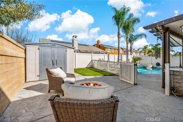 view of patio / terrace with an outdoor fire pit, a fenced backyard, an outbuilding, and a storage unit