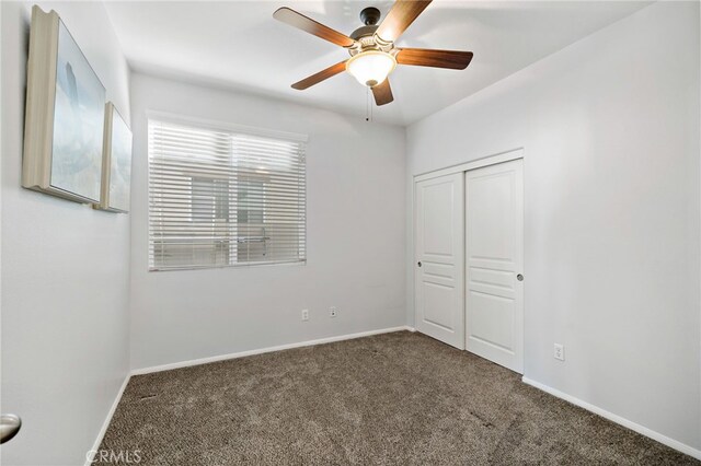 unfurnished bedroom with a closet, carpet flooring, a ceiling fan, and baseboards