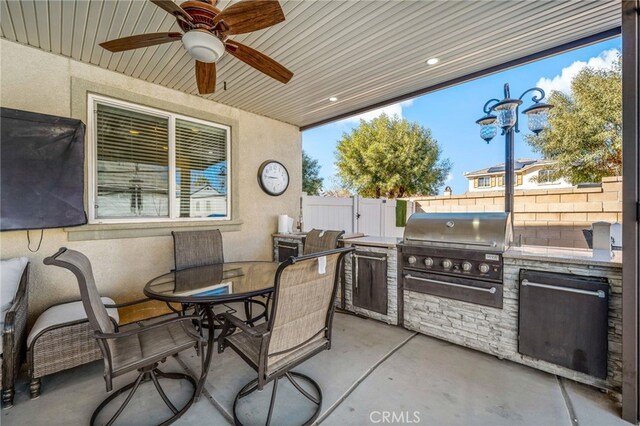 view of patio / terrace featuring ceiling fan, outdoor dining area, fence, exterior kitchen, and grilling area