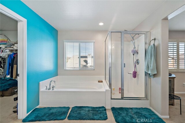 full bath featuring a garden tub, a shower stall, a walk in closet, and baseboards