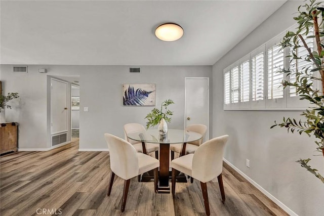 dining room with baseboards, visible vents, and wood finished floors