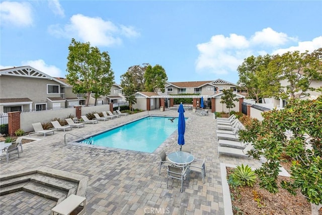 pool with a residential view, a patio area, and fence