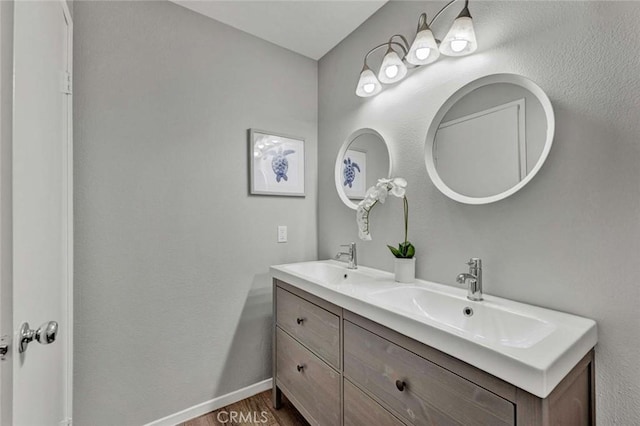 full bathroom with double vanity, baseboards, a sink, and wood finished floors