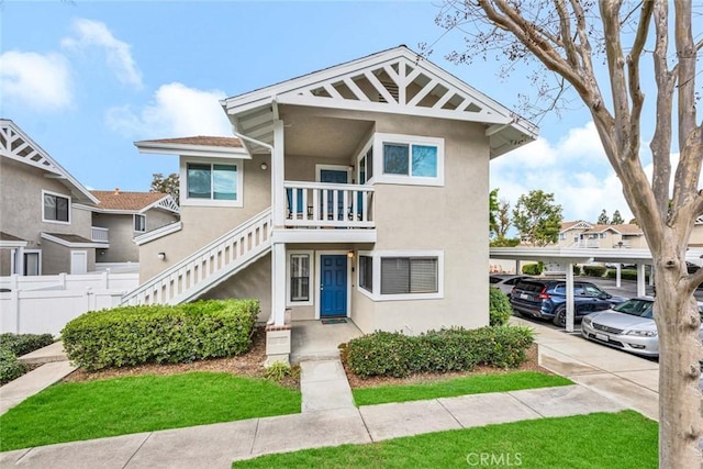 multi unit property featuring stairway, fence, and stucco siding