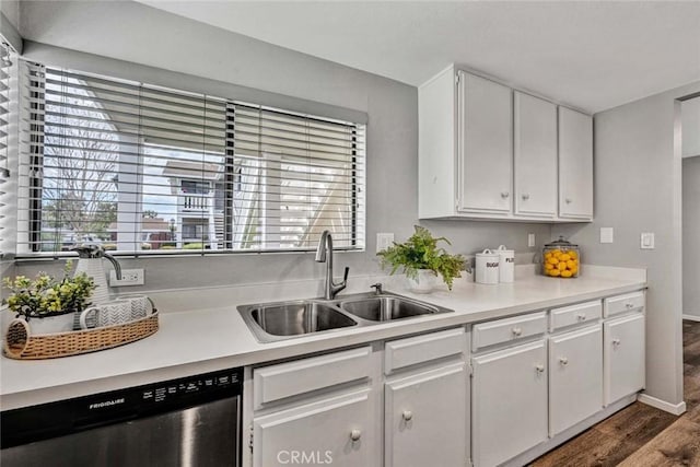 kitchen with dishwasher, wood finished floors, light countertops, white cabinetry, and a sink