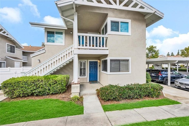 multi unit property featuring fence, stairway, and stucco siding