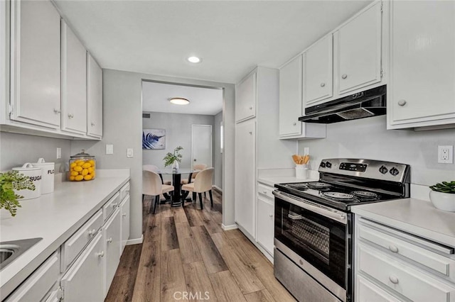 kitchen featuring white cabinets, light wood-style flooring, light countertops, stainless steel range with electric cooktop, and under cabinet range hood