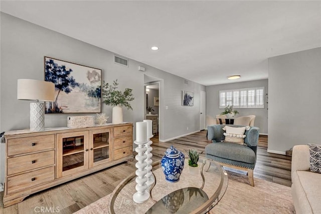 living room featuring wood finished floors, visible vents, and baseboards