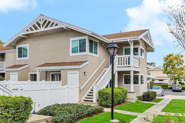 multi unit property featuring stairway, fence, and stucco siding