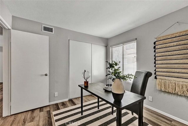 home office featuring baseboards, visible vents, and wood finished floors