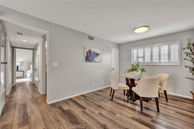 dining room featuring baseboards, visible vents, and wood finished floors