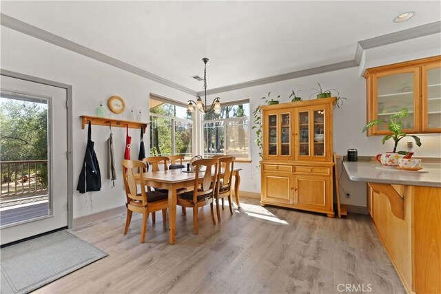 dining space with light wood-style floors, crown molding, baseboards, and an inviting chandelier