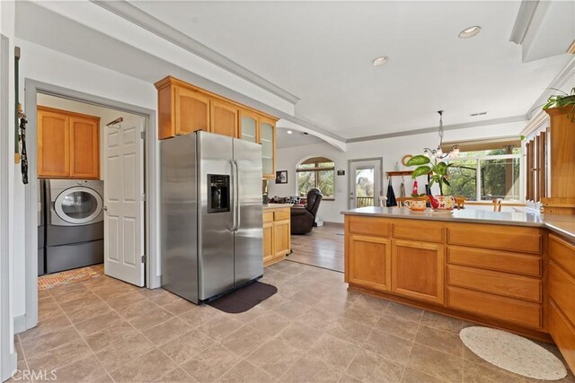 kitchen featuring a notable chandelier, stainless steel refrigerator with ice dispenser, glass insert cabinets, washer / dryer, and a peninsula