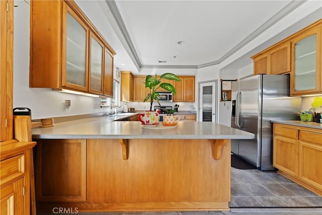 kitchen with glass insert cabinets, a breakfast bar area, a peninsula, stainless steel appliances, and light countertops