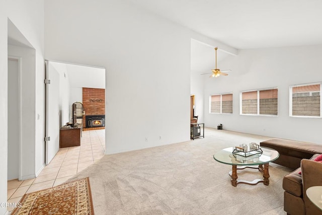 living area with a fireplace, light tile patterned floors, light colored carpet, ceiling fan, and high vaulted ceiling