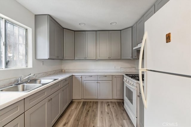818 Record Ave, East Los Angeles, CA 90063 - kitchen with white appliances, gray cabinetry, a sink, light wood-style flooring, and under cabinet range hood