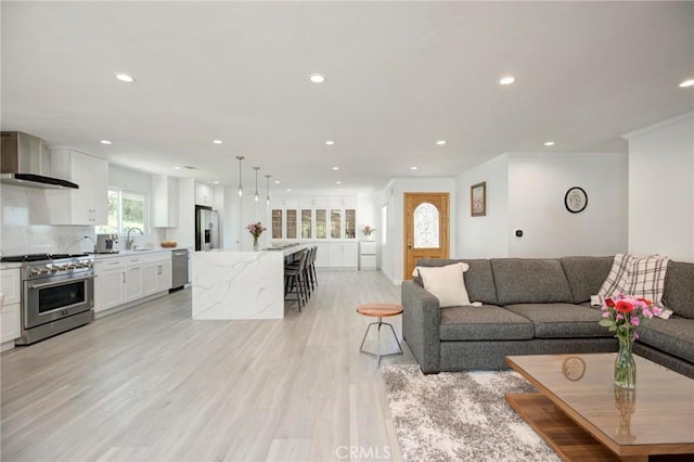 living area with light wood finished floors, recessed lighting, and crown molding