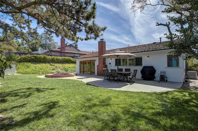 back of property featuring stucco siding, a lawn, cooling unit, and a patio area