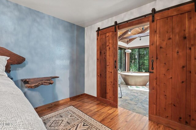 bathroom featuring a soaking tub, wood finished floors, and baseboards