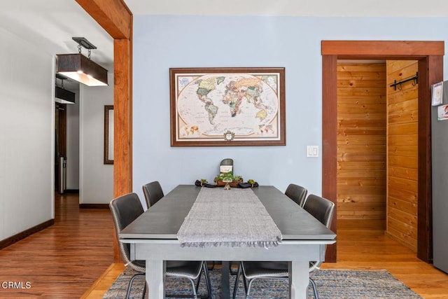 dining space featuring beam ceiling, wood finished floors, and baseboards