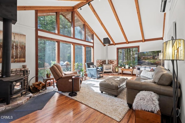 living room featuring beam ceiling, high vaulted ceiling, wood finished floors, and a wood stove