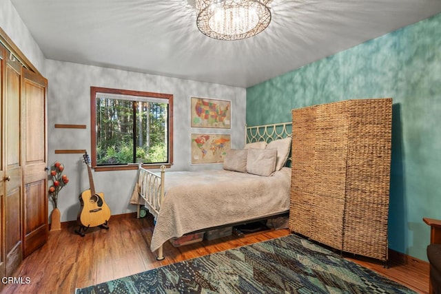 bedroom featuring wood finished floors, baseboards, and a chandelier