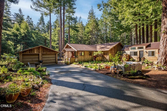 rustic home featuring an outdoor structure, a wooded view, and a garage