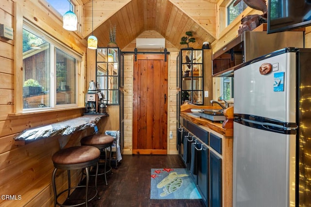 kitchen featuring wood walls, wooden ceiling, freestanding refrigerator, and a barn door