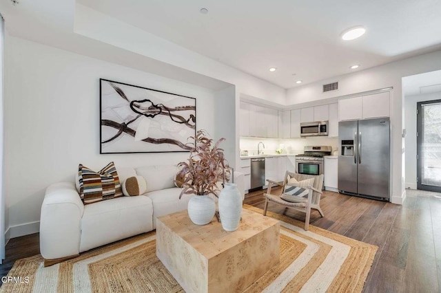 living room with baseboards, wood finished floors, visible vents, and recessed lighting