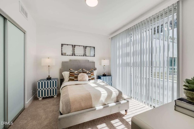 carpeted bedroom with a closet, radiator, visible vents, and multiple windows