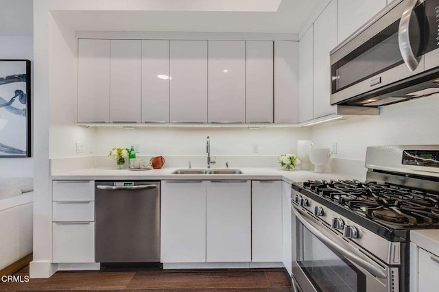 kitchen featuring appliances with stainless steel finishes, light countertops, a sink, and modern cabinets