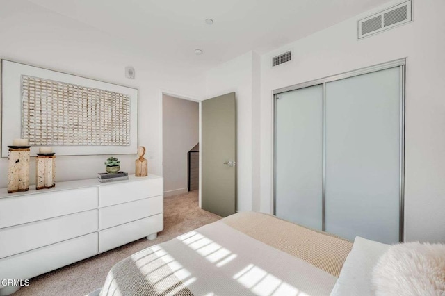 bedroom with visible vents, a closet, and light colored carpet