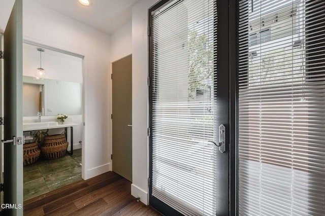 doorway featuring a sink, dark wood finished floors, and baseboards