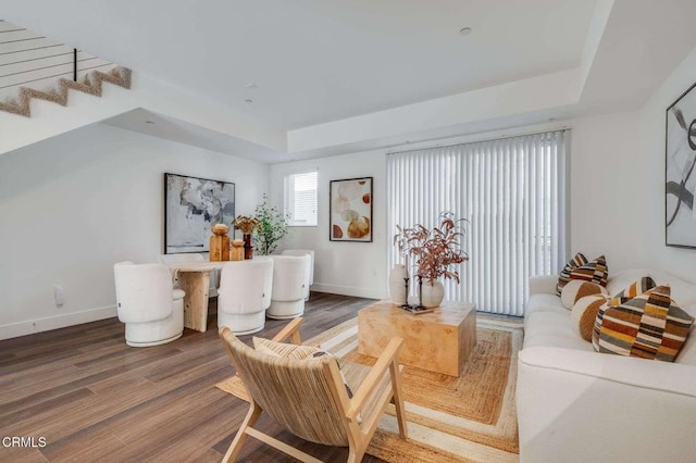 sitting room with baseboards, stairs, a tray ceiling, and wood finished floors