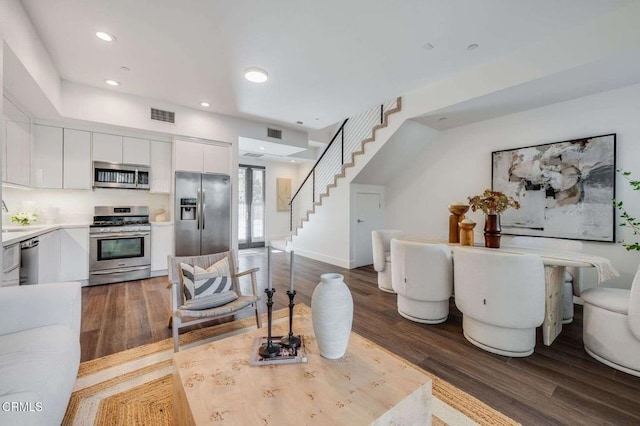 living room with baseboards, stairs, wood finished floors, and visible vents