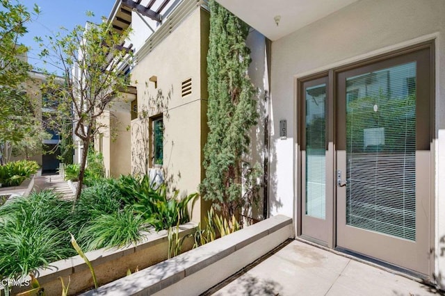 entrance to property featuring french doors and stucco siding