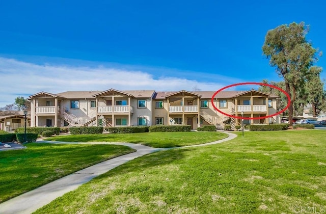 view of property's community featuring a residential view, stairway, and a lawn