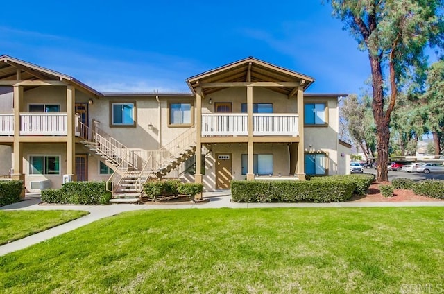 view of front of home featuring stairs, a front lawn, and stucco siding