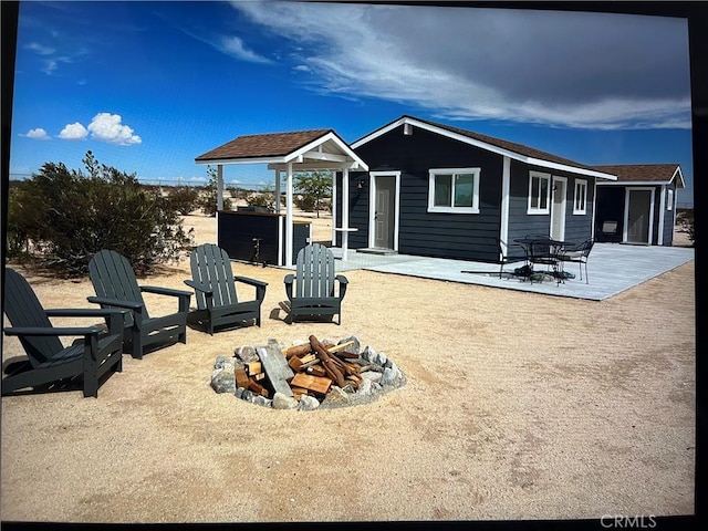 rear view of property featuring a fire pit and an outdoor structure