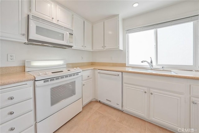 kitchen with white appliances, light tile patterned floors, light countertops, white cabinetry, and a sink