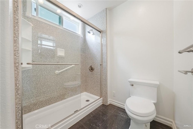 bathroom featuring a stall shower, baseboards, and toilet