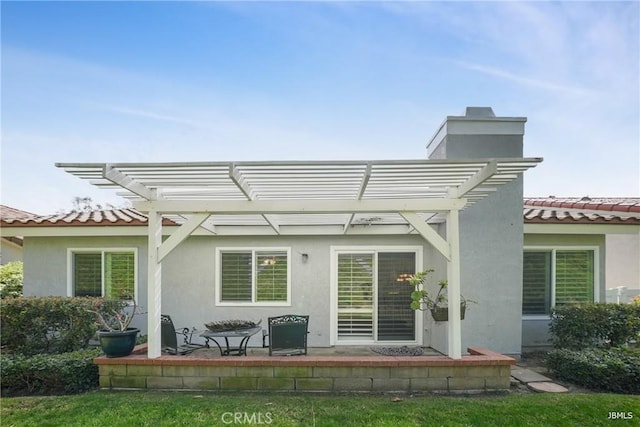 back of property featuring a pergola, a tiled roof, and stucco siding